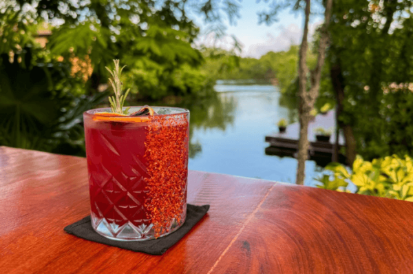 red cocktail on outdoor table with canal waters